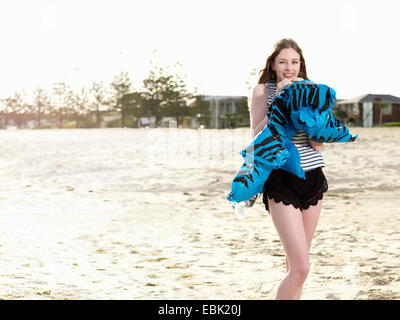 Young woman Blowing up inflatable on beach Banque D'Images