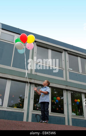 Élève de primaire let fly air ballons en face de son école, Allemagne Banque D'Images