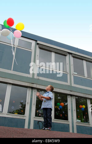 Élève de primaire let fly air ballons en face de son école, Allemagne Banque D'Images