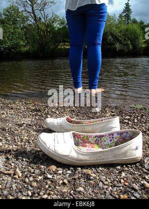 Fille pagayer dans le flux avec chaussures sur bank Banque D'Images