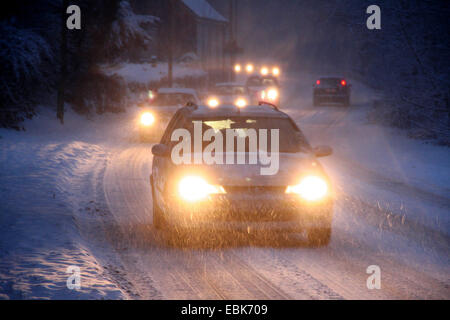 Le trafic lent on a snowy street dans la soirée, l'Allemagne, Rhénanie du Nord-Westphalie Banque D'Images