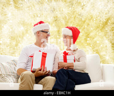 Happy senior couple in santa hats avec boîtes cadeaux Banque D'Images