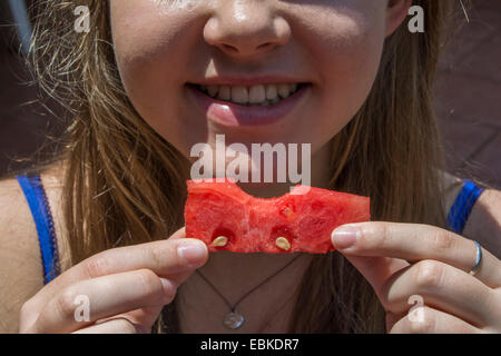 Une jeune fille tenant un morceau de pastèque avec une bouchée de c Banque D'Images