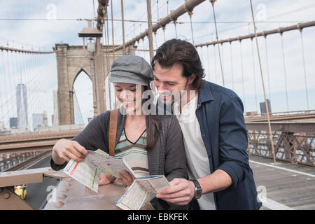 USA, l'État de New York, New York City, Brooklyn, heureux couple reading map on Brooklyn Bridge Banque D'Images