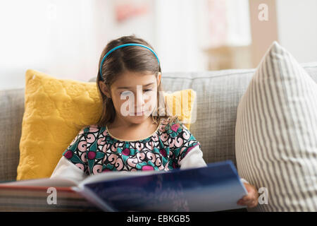 Girl (6-7) reading book at home Banque D'Images