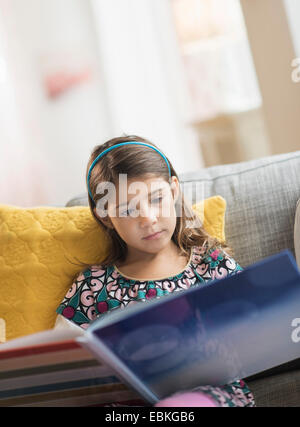 Girl (6-7) reading book at home Banque D'Images