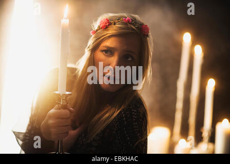 Sorceress holding candle in dark room Banque D'Images