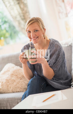 Femme assise sur un canapé et boire du café Banque D'Images