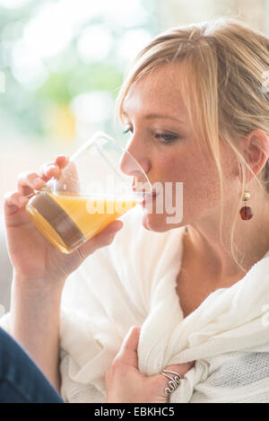 Femme assise dans la salle de séjour et de boire le jus d'orange Banque D'Images