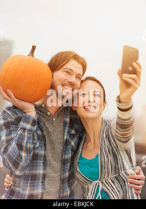 En couple avec selfies téléphone mobile, man holding pumpkin Banque D'Images