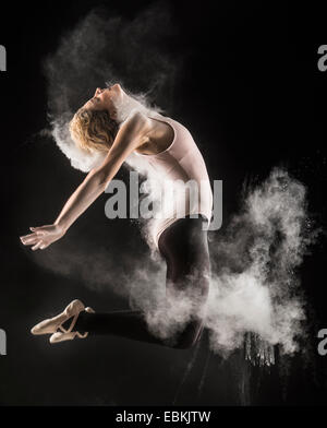 Jeune Danseur Effectuant Un Saut Sur Un Ballet De Fond Noir Gelant L'image  Avec De La Poussière Ou De La Farine