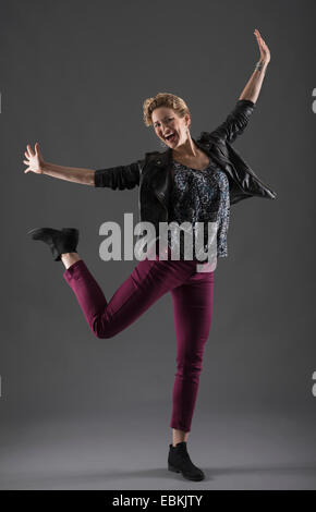 Studio shot of cheerful woman with arms raised Banque D'Images
