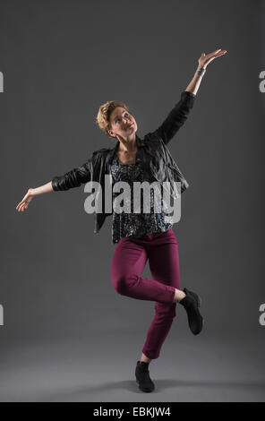 Studio shot of cheerful woman with arms raised Banque D'Images