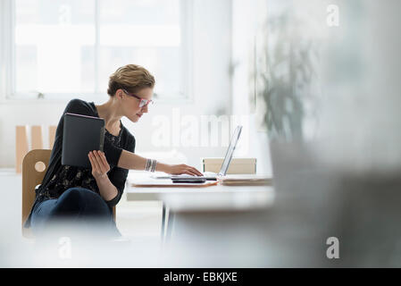 Businesswoman using laptop in office Banque D'Images