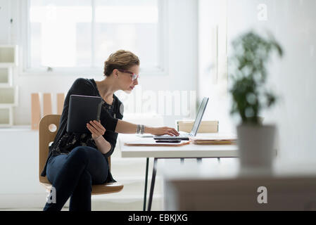 Businesswoman using laptop in office Banque D'Images