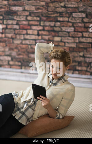 Young woman lying on floor and using digital tablet Banque D'Images