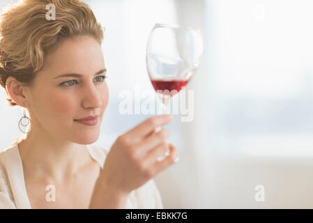 Jeune femme examinant le vin rouge Banque D'Images