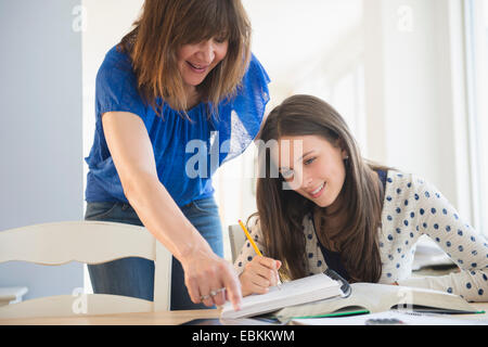 Mother helping daughter (14-15) à faire leurs devoirs Banque D'Images