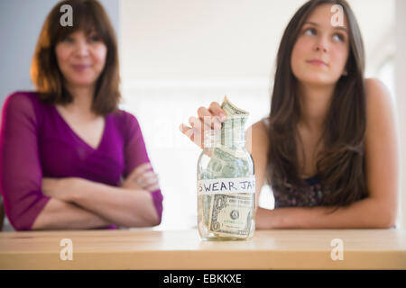 Teenage girl (14-15) mettre de l'argent à prêter jar Banque D'Images