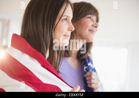 Teenage girl (14-15) et sa mère enveloppé dans le drapeau américain sur la quatrième de Juillet Banque D'Images