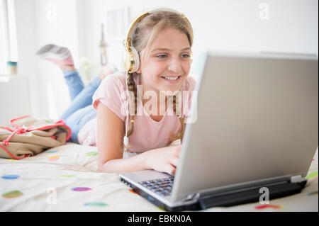 Girl (12-13) Lying in Bed using laptop Banque D'Images