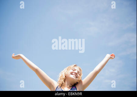 Girl (12-13) with arms raised, smiling Banque D'Images