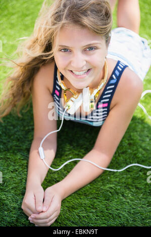 Girl (12-13) lying in grass with headphones Banque D'Images