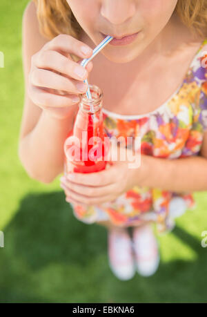 Girl (12-13) boisson de la bouteille à l'aide de la paille Banque D'Images