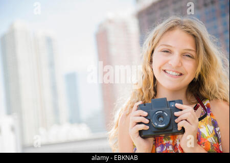USA (New Jersey), Girl (12-13) holding camera, smiling Banque D'Images