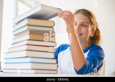 Portrait of teenage girl (12-13) stacking books Banque D'Images