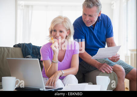 Portrait of couple sitting on sofa using laptop Banque D'Images