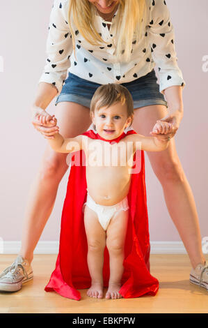 Studio shot of mother holding baby daughter (18-23 mois) en costume Banque D'Images