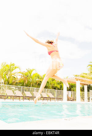 USA, Floride, Jupiter, Woman jumping into swimming pool Banque D'Images