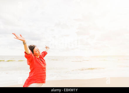 USA, Floride, Jupiter, Side view of woman standing with arms up on beach Banque D'Images