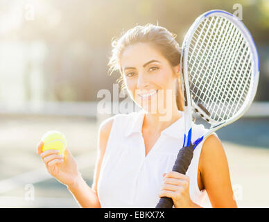 Portrait of young woman holding balle de tennis et tennis racket Banque D'Images