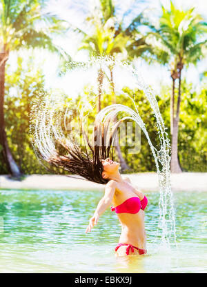 USA, Floride, Jupiter, Portrait of young woman wearing bikini tossing sèche et aux projections d'eau dans le lagon tropical Banque D'Images