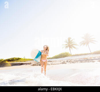 USA, Floride, Jupiter, young woman running in surf surfboard comptable Banque D'Images