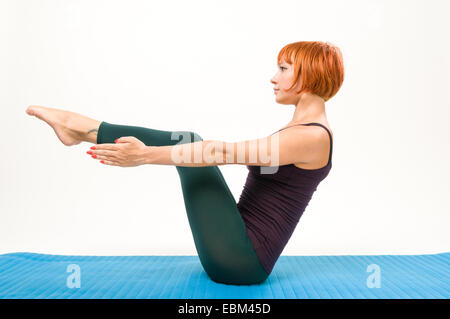 Belle femme aux cheveux rouge remise en forme pratiquant le yoga en studio Banque D'Images