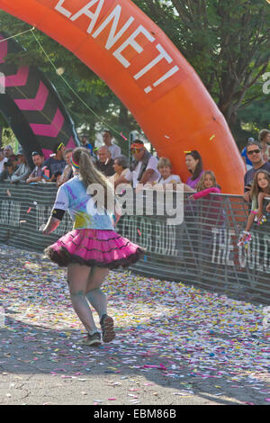 Un heureux runner éclaboussés de teintures colorées s'approche de la ligne d'arrivée dans l'Asheville 5K Color Run Banque D'Images