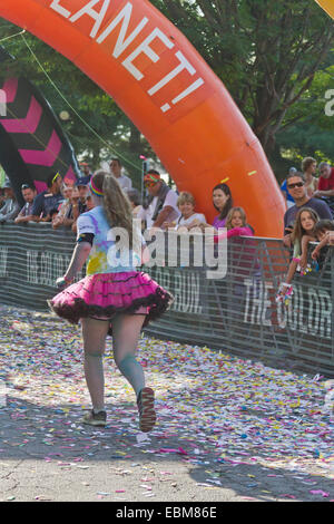 Un heureux runner éclaboussés de teintures colorées s'approche de la ligne d'arrivée dans l'Asheville 5K Color Run Banque D'Images