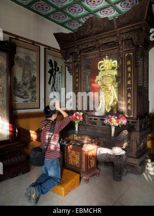 Jeune homme adorant un Buddah statue en or au Da Ci'en temple de Xian, Chine Banque D'Images