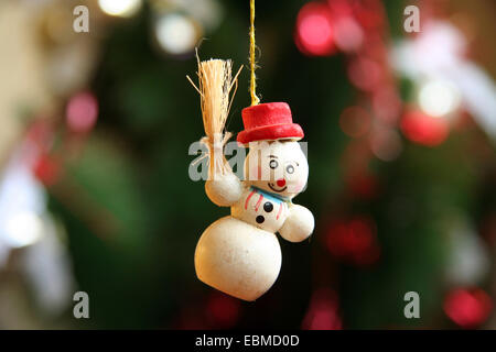 Le Snowman Christmas Tree decoration avec Red Hat et la tenue de feuilles de maïs est suspendu par un fil avec zone de sapins vert foncé Banque D'Images