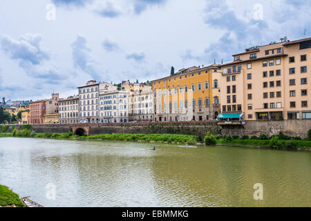 Aperçu de l'Arno à Ponte Vecchio à Florence avec ses maisons typiques et des canoës sur l'eau dans un jour nuageux Banque D'Images