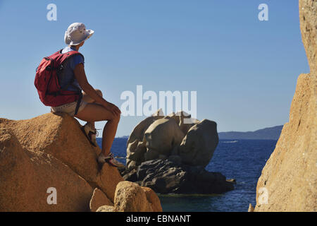 Wanderer femme assise sur un rocher et à admirer la vue sur le cours d'une étrange formation rocheuse, France, Corse Banque D'Images