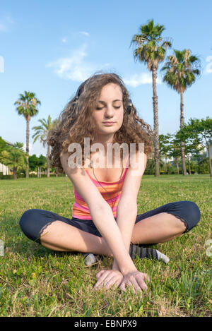 Woman doing yoga dans le parc avec des arbres Banque D'Images