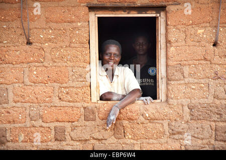 Deux femmes regardant par la fenêtre d'une maison en brique où ils font de l'alimentation de la farine de maïs, Burundi, Mvugo, Nyanza Lac Banque D'Images