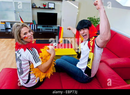 Deux terrains de soccer fans célébrer dans la salle de séjour, Allemagne Banque D'Images