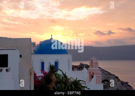 Ia, Santorin, Grèce, sud de la Mer Egée. Aube du ciel coloré, typique de l'église à dôme bleu en premier plan. Banque D'Images