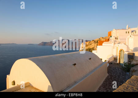 Ia, Santorin, Grèce, sud de la Mer Egée. Les bâtiments typiques de clifftop éclairées par le soleil levant. Banque D'Images