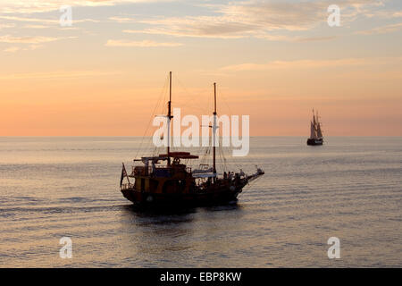 Ia, Santorin, Grèce, sud de la Mer Egée. Voiliers dans la baie après le coucher du soleil. Banque D'Images